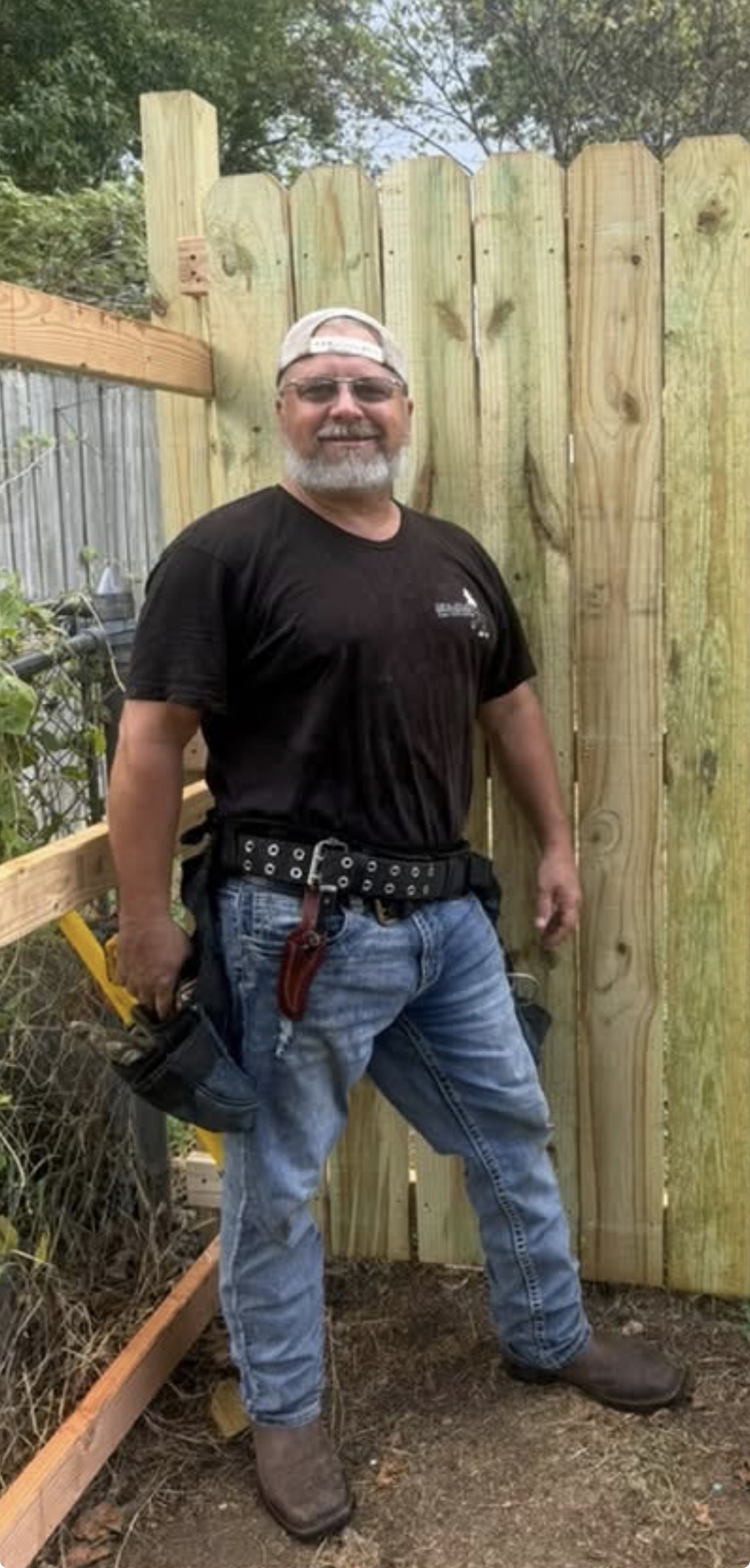 Fence builder standing beside a new wood fence